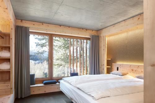 a bedroom with a large bed and a large window at Alpine Lodge Chesa al Parc in Pontresina
