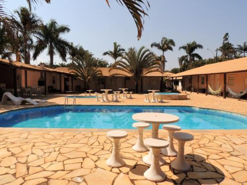 a swimming pool with a table and stools in front of a resort at Hotel Fazenda Raiz Mineira - Estamos a 21,2 km de Carmo do Rio Claro in Conceição da Aparecida