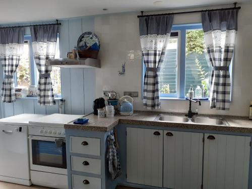 eine Küche mit weißen Schränken, einem Waschbecken und Fenstern in der Unterkunft Authentic fisherman s house in the center of Edam in Edam