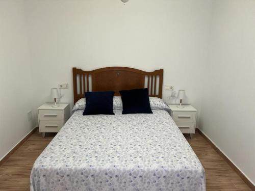 1 dormitorio con 1 cama con almohadas azules y 2 mesitas de noche en Agradable casa familiar en Pliego. en Pliego