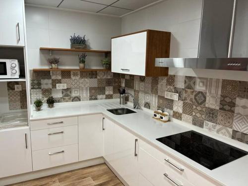 uma cozinha com armários brancos e um lavatório em Agradable casa familiar en Pliego. em Pliego