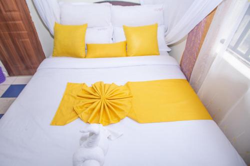 a bedroom with a bed with yellow pillows at Happy Springs Hotel & Accomodation in Kericho