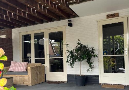 a porch of a house with a bench and windows at Sous aan Zee in Noordwijk