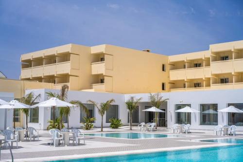 ein Hotel mit einem Pool, Stühlen und Sonnenschirmen in der Unterkunft Dar Khayam in Hammamet