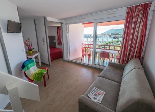 a living room with a couch and a large window at Résidence Mer & Golf Sokoburu in Hendaye