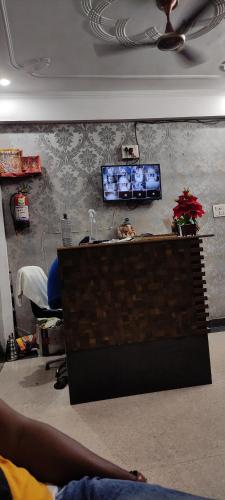 a living room with a tv on a wall at hotel tridev inn in Allahābād