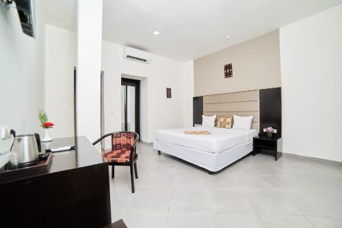 Schlafzimmer mit einem großen weißen Bett, einem Schreibtisch und einem Stuhl in der Unterkunft Dunia Hotel Bamako in Bamako