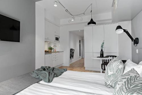 a white bedroom with a bed and a kitchen at Forenom Hotels & Apartments Kista in Stockholm