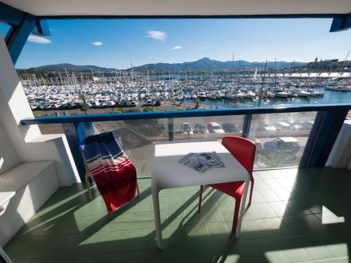 a balcony with a table and a chair and a marina at Résidence Mer & Golf Sokoburu in Hendaye