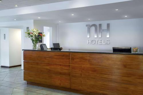 NH Iquique Costa في إكيكي: مكتب استقبال في لوبي الفندق مع إناء من الزهور