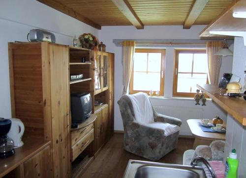 a kitchen with a tv and a chair in a room at Familienferienhof Sell´s Scheune in Sundhausen