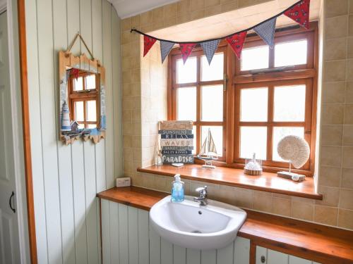 ein Badezimmer mit Waschbecken und Fenster in der Unterkunft Barley Cottage in Axminster
