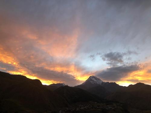 a sunset over a mountain range with the sky at Hotel Nestt in Stepantsminda