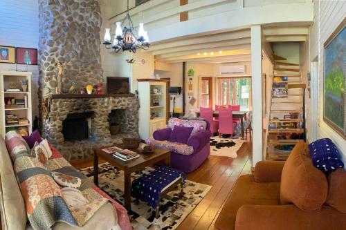a living room with purple furniture and a stone fireplace at Casa Estilo Canadense - Canela in Canela