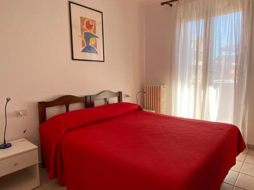 a red bed in a bedroom with a window at Ville sul Mare in Marina di Grosseto