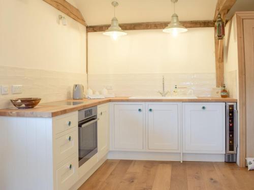 a kitchen with white cabinets and a sink at Rushmoor Lodge in Admaston