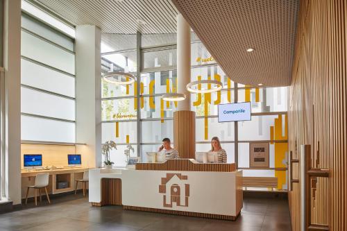 een lobby met twee mensen aan een bureau in een gebouw bij Hotel Campanile Paris-Bercy Village in Parijs