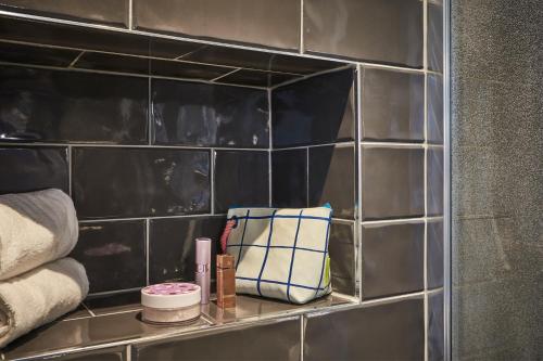 a shelf in a bathroom with towels and cosmetics at CAMPANILE PARIS 12 - Bercy Village in Paris
