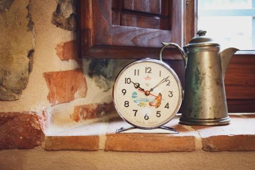 a clock and a tea kettle sitting on a window sill at Casa Il giuggiolo in Giuncarico