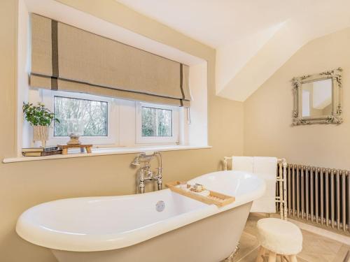 een badkamer met een wit bad en een raam bij Keepers Cottage in Durisdeer