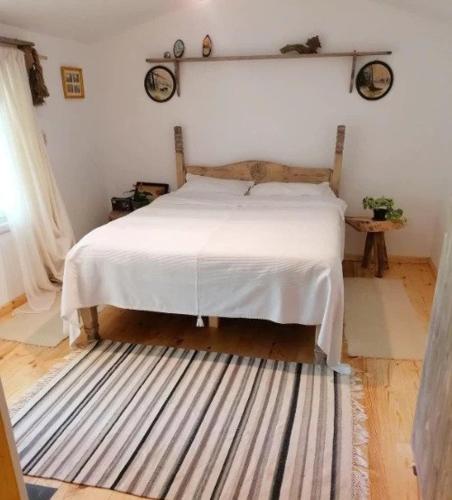 a bedroom with a white bed and a striped rug at Casa de oaspeti adorabila aproape de natura in Sărata-Monteoru