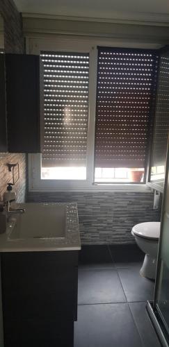 a bathroom with a sink and a toilet and two windows at ARREBOL in Navarrete