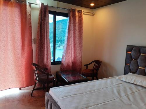 a bedroom with a bed and two chairs and a window at Lake Haven Resort, Sari, Chopta in Sari