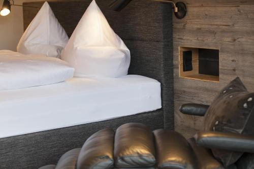 a bedroom with two beds with white sheets and brown leather seats at Boutique Hotel Gams in Oberstdorf