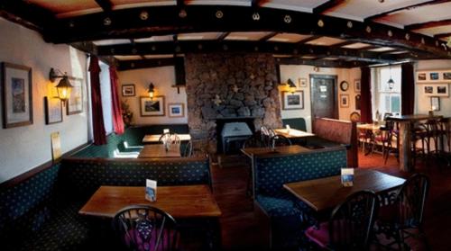 a restaurant with tables and chairs and a stone wall at Strands Hotel/Screes Inn & Micro Brewery in Nether Wasdale