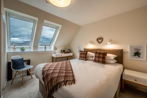 1 dormitorio con 1 cama grande y 2 ventanas en Newton Lodge en Unapool