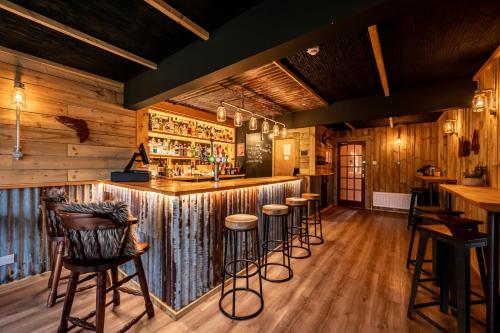 a bar with wooden walls and bar stools at Newton Lodge in Unapool