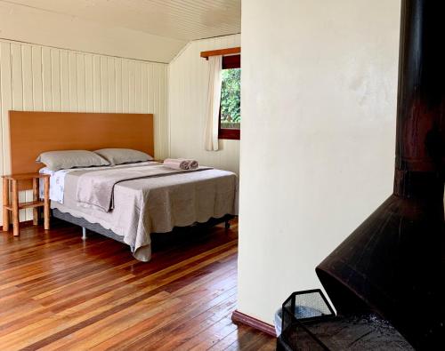 um quarto com uma cama e piso em madeira em Central Chalés em Cambará