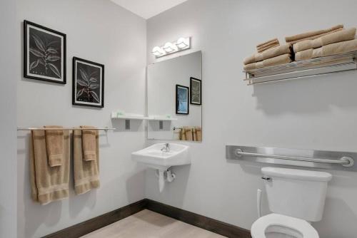 a white bathroom with a toilet and a sink at Barnwood Suite - Main Street Lodge in Berlin in Berlin