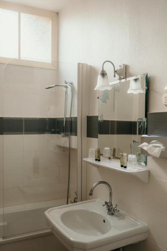 a white bathroom with a sink and a shower at Hôtel Le Cro-Magnon in Les Eyzies-de-Tayac