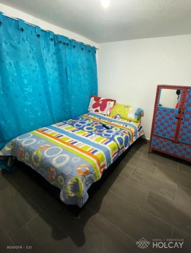 a bedroom with a bed and a blue curtain at Hospedaje Holcay in Bogotá