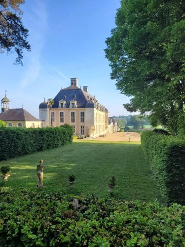 Un homme debout dans l'herbe devant une grande maison dans l'établissement Château du Boschet chambre Pierre de Lescouet, à Bourg-des-Comptes