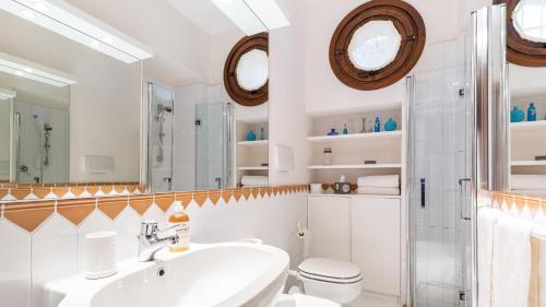 bagno con lavandino, servizi igienici e specchio di CORAZZA 6&1, Emma Villas a Torri del Benaco