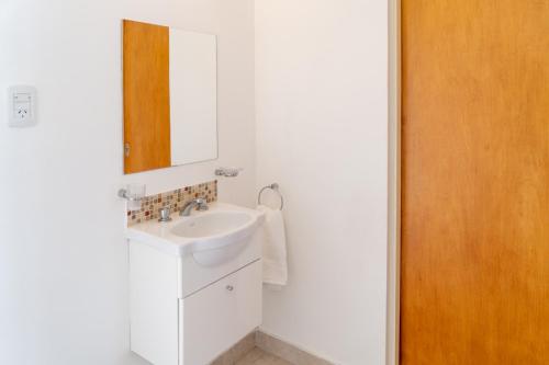 Baño blanco con lavabo y espejo en Moana Alojamientos en Junín