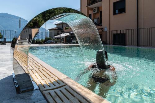een jongen zwemt onder een fontein in een zwembad bij Hotel Sole in San Siro
