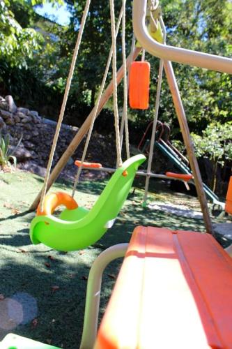 a green swing in a playground with a bench at Comfortable Apartment with Pool in Marco de Canaveses - 50 m² in Marco de Canavezes