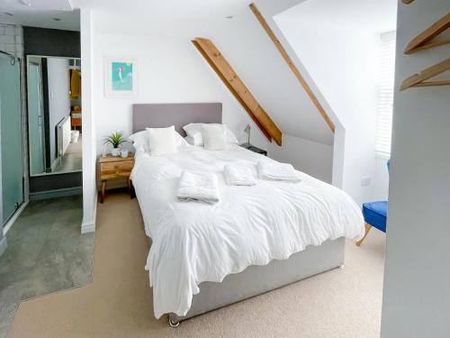 a bedroom with a large bed with white sheets and pillows at Sleeps 16 with style and space- and a hot tub! in Newquay