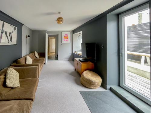 a living room with a couch and a tv at Sleeps 16 with style and space- and a hot tub! in Newquay