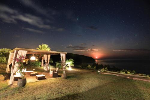 a gazebo at night with a view of the water at Spectacular villa near the beach! in Agia Paraskevi