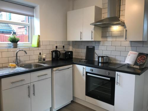 Modern 3-bed house with parking Bamber Bridge, Preston في Bamber Bridge: مطبخ مع دواليب بيضاء ومغسلة