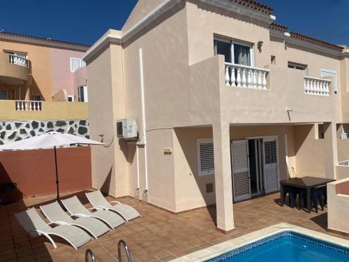 a house with a swimming pool and chairs and an umbrella at Casa Mariben, Vacation Rental home Vv 3 Bedrooms private pool with sea views in Callao Salvaje