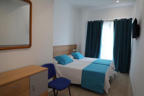 a bedroom with a bed and two blue chairs at Pension Campello The Blue Med in Alicante