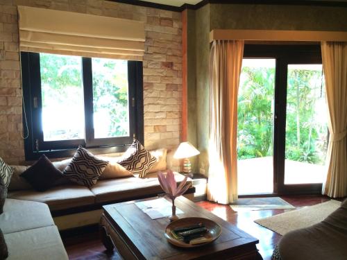 a living room with a couch and two windows at Sunshine Residence in Baan Tai