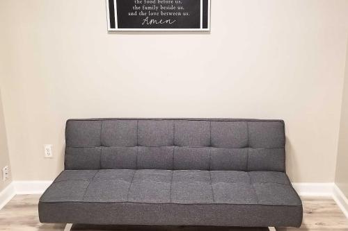 a gray couch in a room with a white wall at Pond-View Deck and Pool Table Woodbridge Haven! in Woodbridge