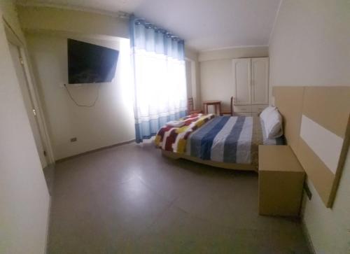 a bedroom with a bed and a television in it at Hotel La Suite de Angelique Huacho in Huacho