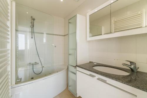 a bathroom with a sink and a shower at Penthouse app met imposant & eindeloos zeezicht in Middelkerke